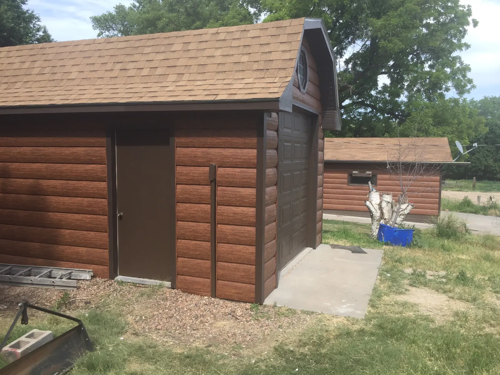 Completed outbuilding siding with matching corner and door trim, showing the finished log-look profile.