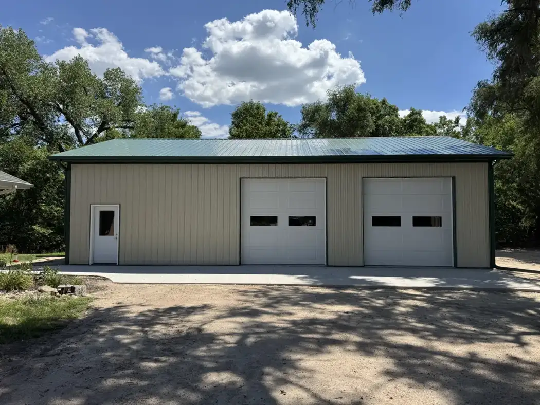 The finished front provides two overhead-door bays and a separate entry door.