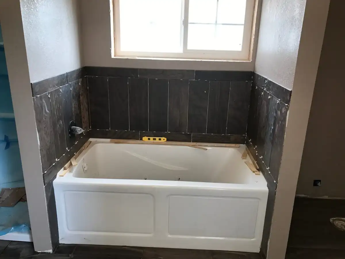 Bathtub with dark tile surround during installation