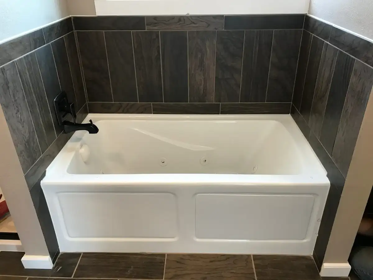 Bathtub with completed dark tile surround and black fixtures
