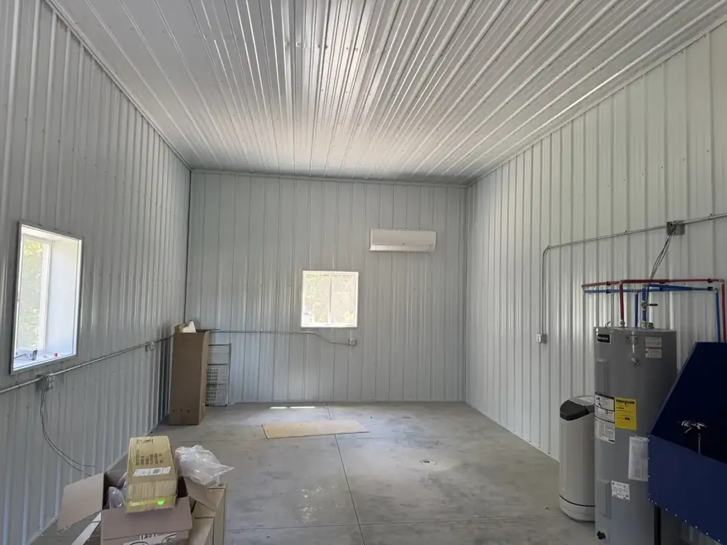 Metal wall and ceiling liners finish the interior, with windows, electrical conduit, and mechanical equipment in place.