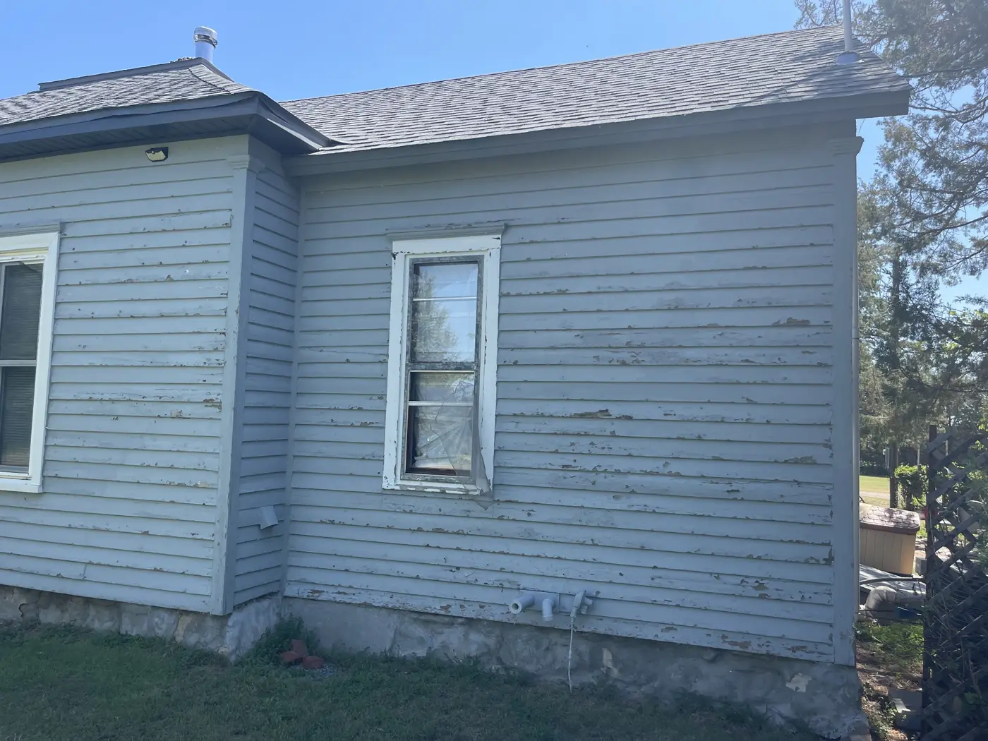 A closer view of the original siding and window trim before replacement.