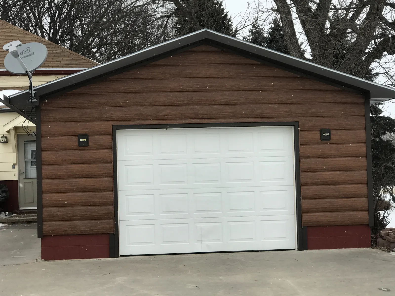 Finished log-look siding across the garage front and gable, with dark trim framing the white overhead door.