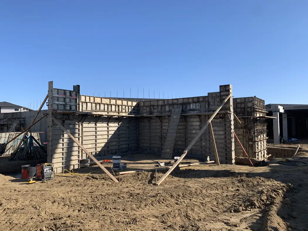 Braced formwork and projecting reinforcement establish the wall geometry.