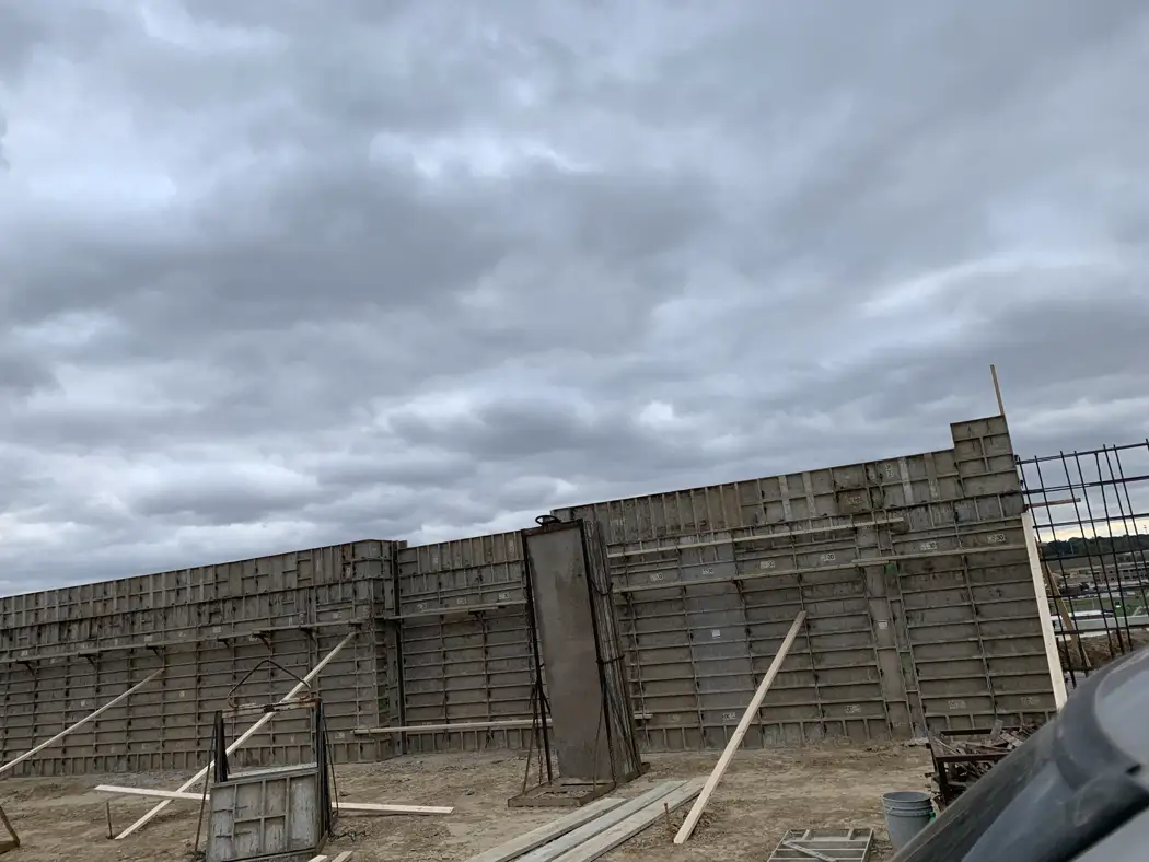 Braced wall forms establish the concrete wall line, with reinforcement visible at the adjoining section.