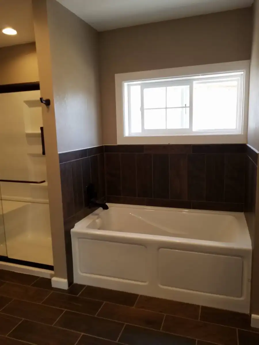 Finished bathtub area with tile wainscot and window