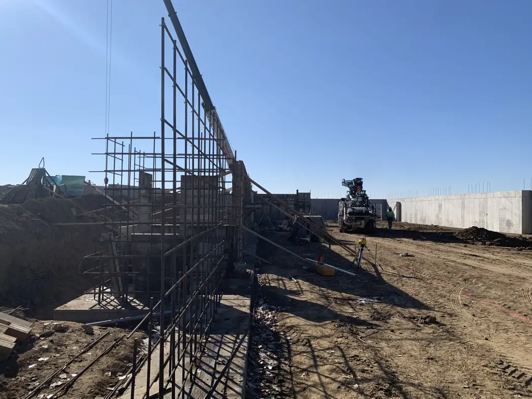 A tall reinforcing steel cage is assembled before the wall forms enclose it.