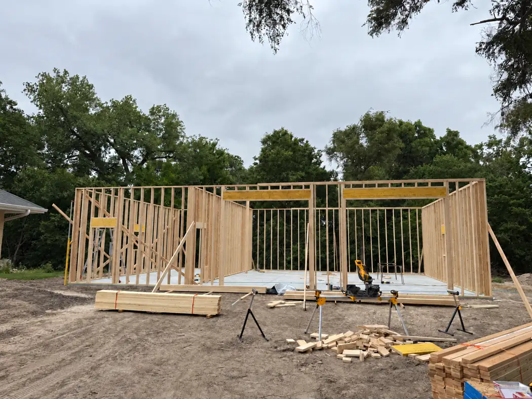 Wood-framed walls and large overhead-door openings rise above the concrete slab.