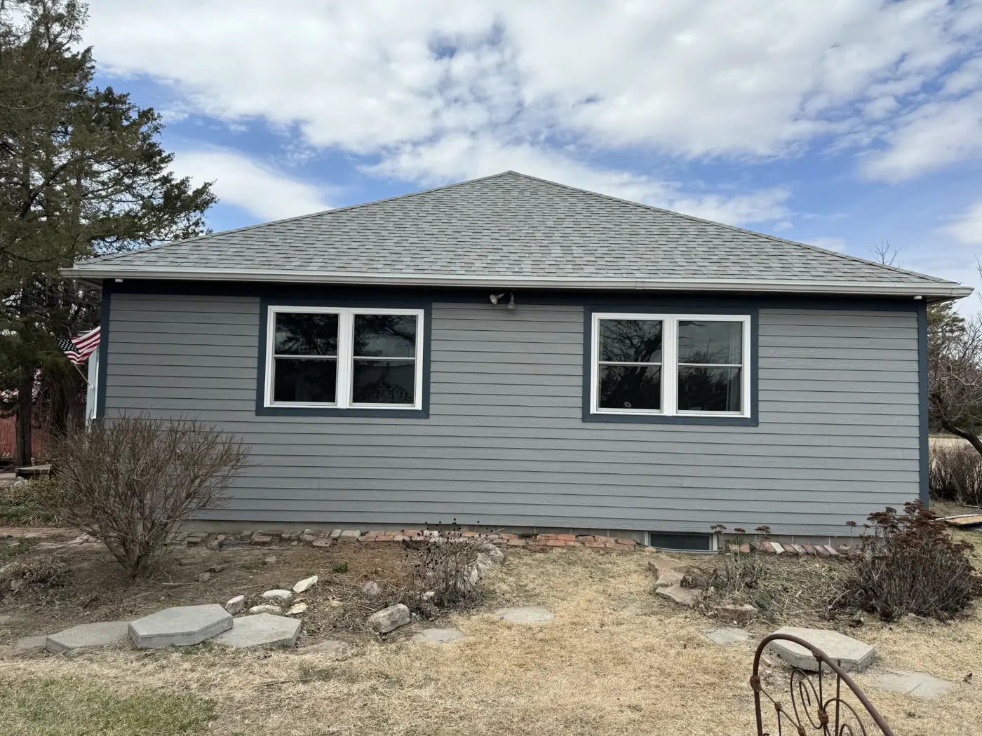New siding and window trim are in place across the front elevation as exterior work advances.